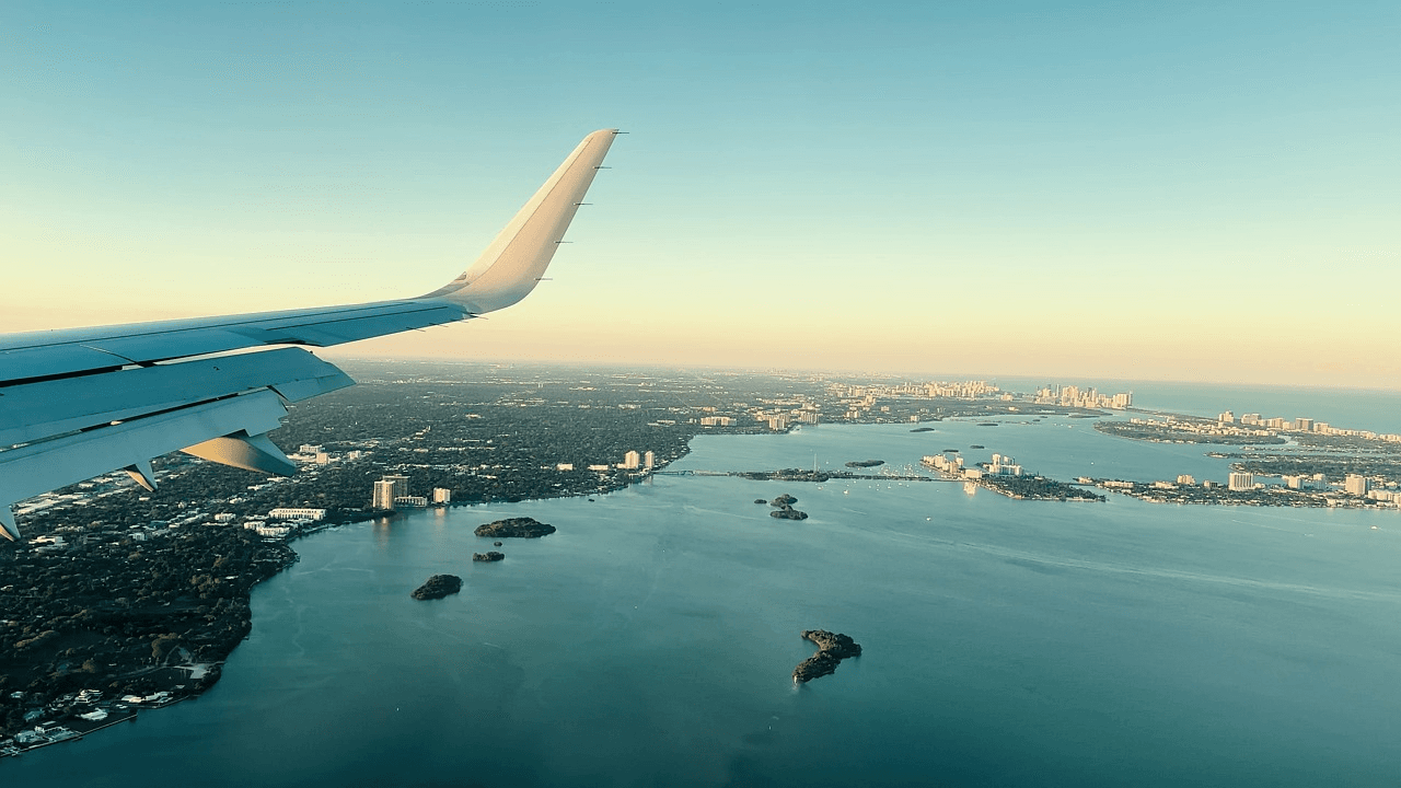 An aircraft wing above a coastal city and its waterways